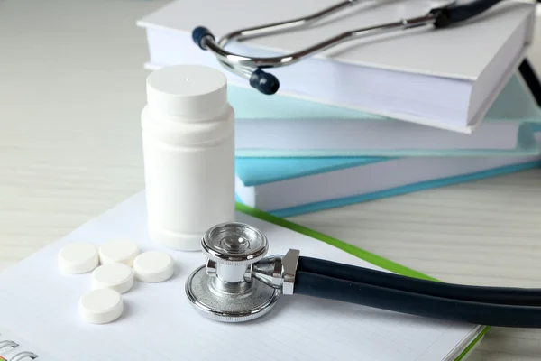 Estetoscópio médico com livros e tablet em mesa de madeira — Fotografia de Stock