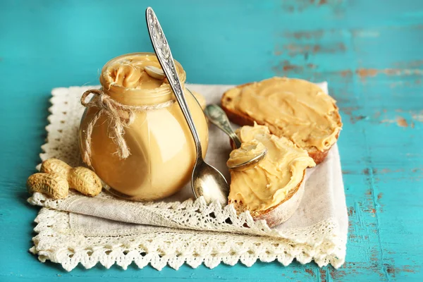 Bela vida morta com manteiga de amendoim fresca em fundo de madeira — Fotografia de Stock