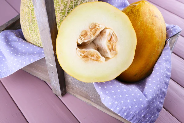 Melone in Holzkiste auf Serviette auf Holztisch — Stockfoto