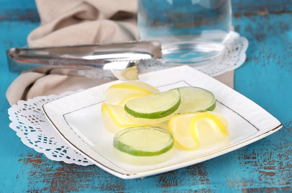 Limón helado en plato y vaso de agua fría sobre fondo de madera de color —  Fotos de Stock