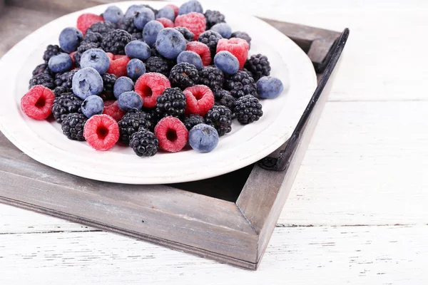 Baies glacées sur assiette, sur fond de bois couleur — Photo