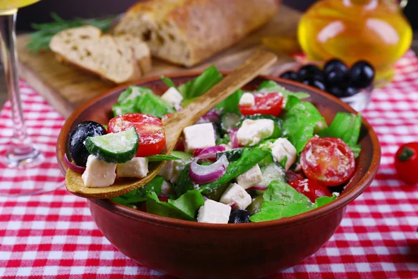 Bowl of Greek salad served with olive oil and bread on fabric background — Stock Photo, Image