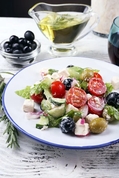 Plate of Greek salad served with wine and olive oil on wooden table on dark background — Stock Photo, Image