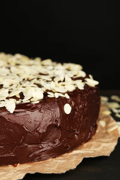 Tasty chocolate cake with almond, on wooden table, on dark background — Stock Photo, Image