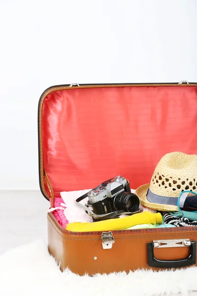 Kvinnliga kläder och fotokamera i gamla resväska på ljus bakgrund — Stockfoto