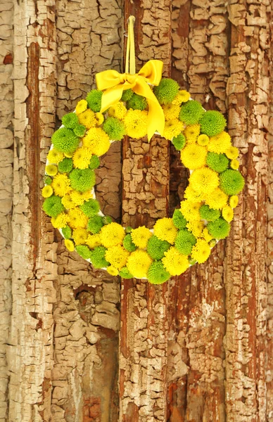 Beautiful wreath of flowers hanging on old wooden door — Stock Photo, Image