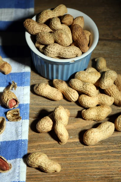 Peanuts on blue napkin, on wooden background — Stock Photo, Image