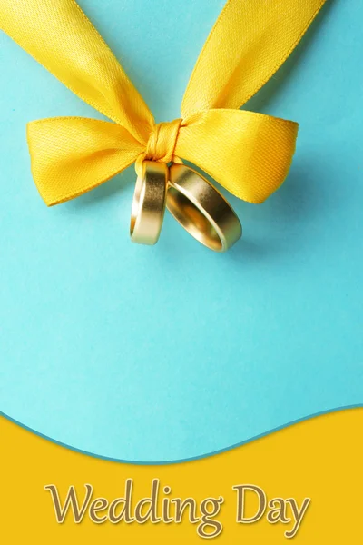 Wedding rings tied with ribbon on color background — Stock Photo, Image