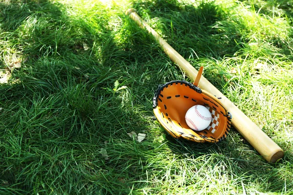 Baseball bat, ball and glove on green grass background — Stock Photo, Image