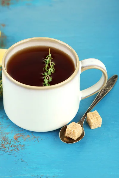 Cup of tasty herbal tea with thyme on blue wooden table — Stock Photo, Image