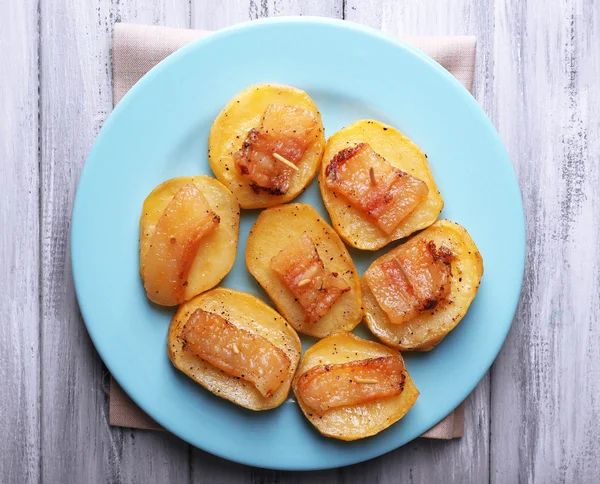 Bakad potatis med bacon på plattan, på trä bakgrund — Stockfoto