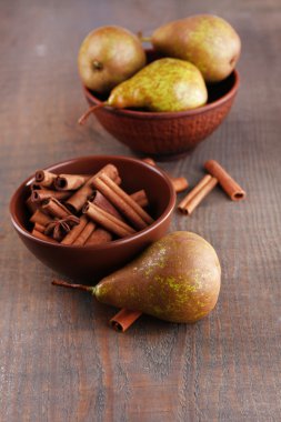 Olgun armut ve tarçın kase, ahşap arka plan üzerinde