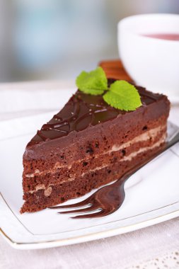 Plaka ve doğal zemin üzerine ahşap masa üzerinde çay fincan çikolatalı kek parçası