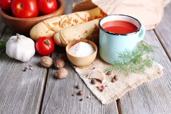 Jus de tomate maison en tasse de couleur, bâtonnets de pain, épices et tomates fraîches sur fond en bois — Photo