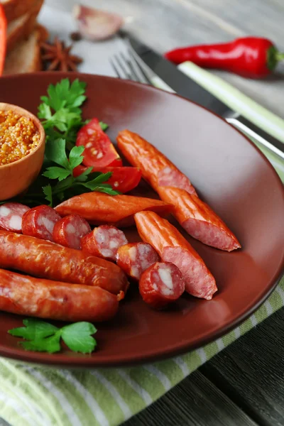 Surtido de sabrosas salchichas finas en plato sobre fondo de madera — Foto de Stock