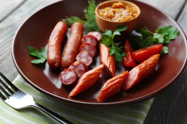 Assortment of tasty thin sausages on plate on wooden background — Stock Photo, Image