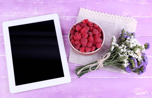Tablet,, ciotola di lamponi e fiori selvatici — Foto Stock