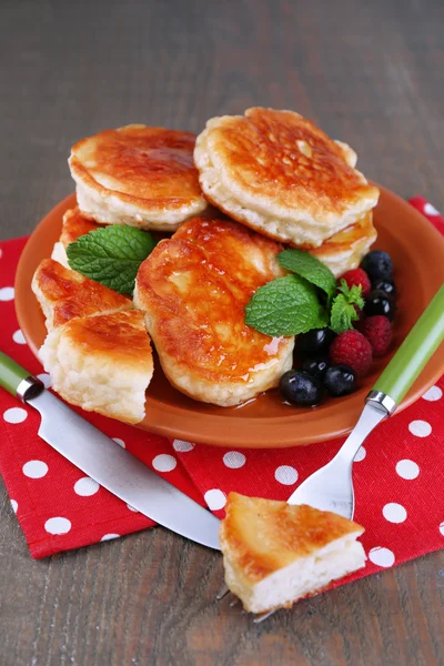 Smakelijke pannenkoeken met verse bessen, honing en mint blad op plaat, op houten achtergrond — Stockfoto