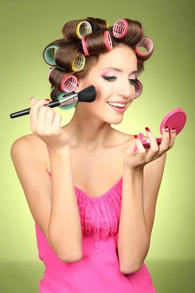 Menina bonita em encrespadores de cabelo no fundo verde — Fotografia de Stock