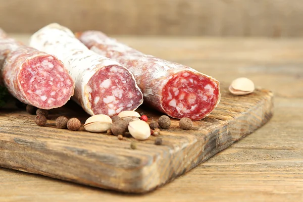 Salame italiano em tábua de corte de madeira, sobre fundo de madeira — Fotografia de Stock