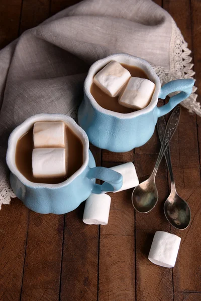 Cups of coffee with marshmallow and napkin on wooden table — Stock Photo, Image
