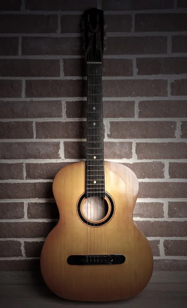 Guitar på gulvet nær murstensvæg - Stock-foto