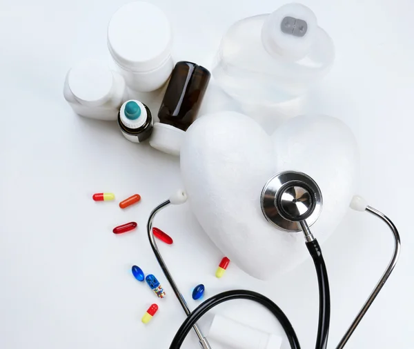Стетоскоп, белое сердце и таблетки — стоковое фото