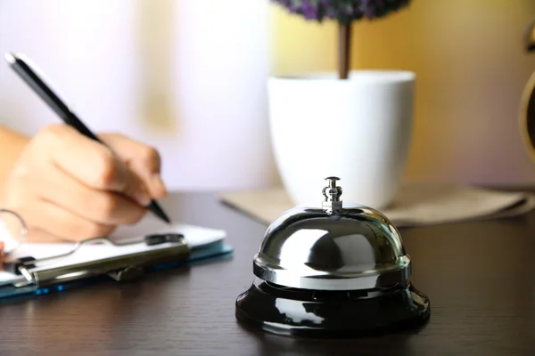 Female hand  writing in Hotel guest book on reception desk, on bright background — Stock Photo, Image