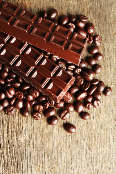 Kaffebønner med sjokoladeglasur og mørk sjokolade på trebakgrunn – stockfoto