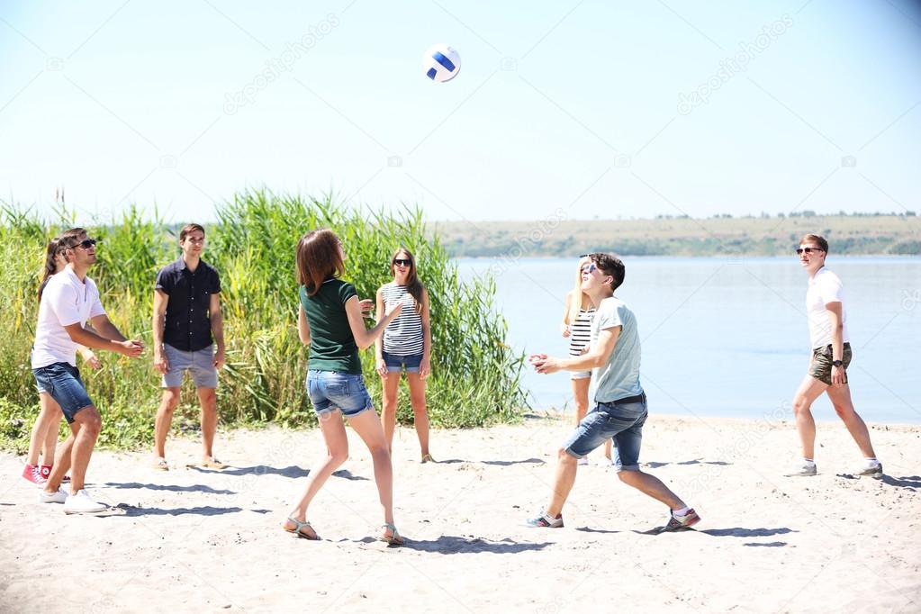 young people playing volleyball on beach