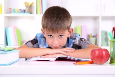 школяр, сидячи на столі в класі