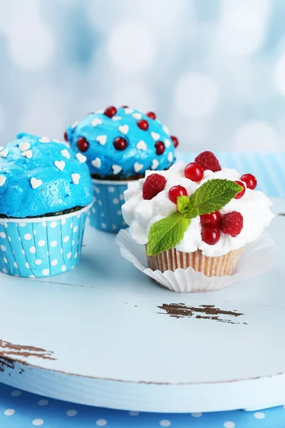 Sabrosos cupcakes en la mesa, sobre fondo brillante —  Fotos de Stock