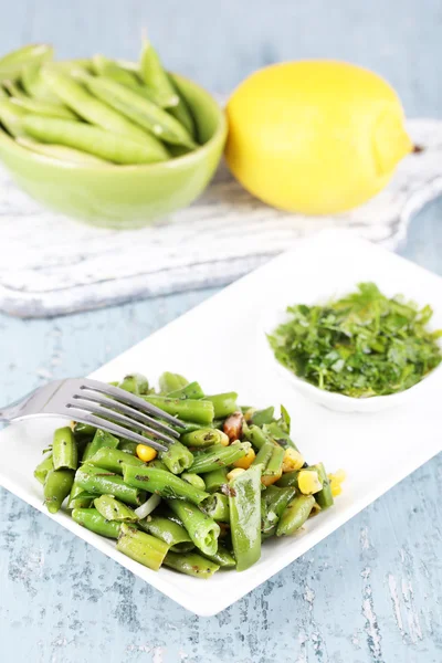 Salat mit grünen Bohnen und Mais auf Teller, auf farbigem Holzgrund — Stockfoto