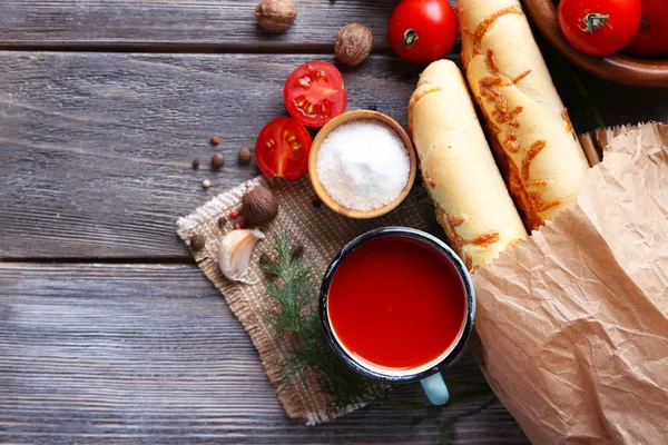 Zelfgemaakte tomatensap in kleur mok, brood stokken, specerijen en verse tomaten op houten achtergrond — Stockfoto