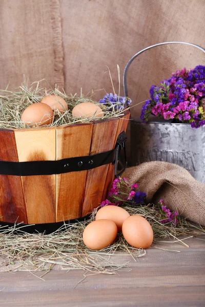 Cesta redonda grande con hierba seca y huevos frescos sobre fondo de saco —  Fotos de Stock