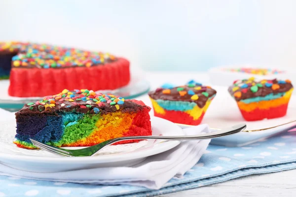 Delicioso pastel de arco iris en el plato, en la mesa, sobre fondo claro — Foto de Stock