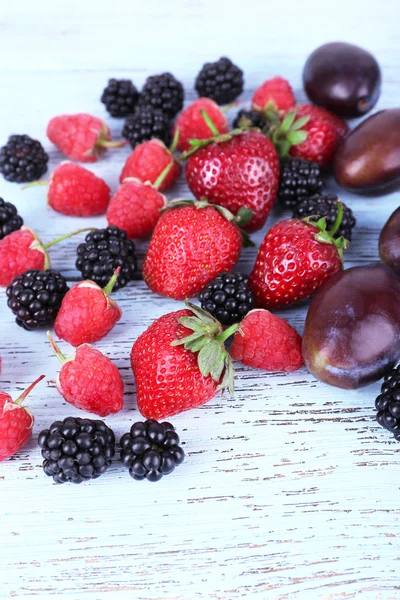 Different berries and plums on wooden table close-up — Stock Photo, Image