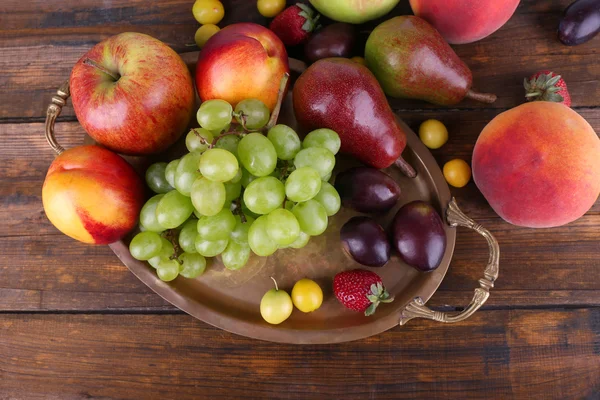 Διαφορετικές μούρα και φρούτα σε δίσκο σε κοντινό πλάνο ξύλινο τραπέζι — Φωτογραφία Αρχείου