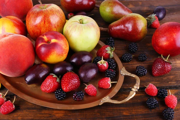 Bagas diferentes e frutas na bandeja em close-up de mesa de madeira — Fotografia de Stock