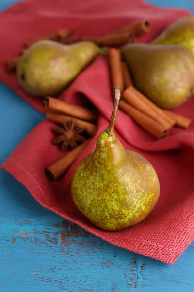 Rijpe peren en kaneelstokjes op een houten achtergrond kleur — Stockfoto