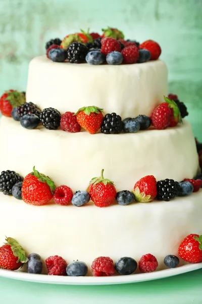 Krásný svatební dort s ovocem na barevné dřevěné pozadí — Stock fotografie