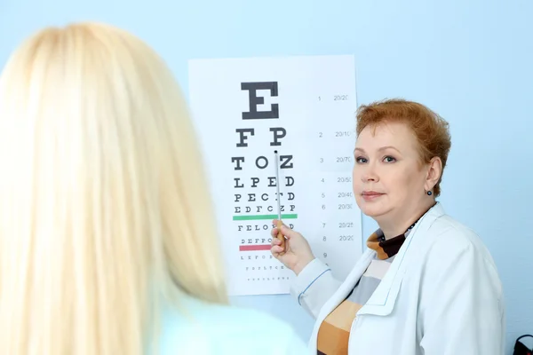 Concepto de optometría: mujer joven y bonita que tiene los ojos examinados por un oftalmólogo — Foto de Stock