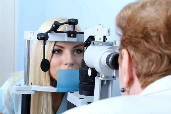 Optometry concept - pretty young woman having her eyes examined by eye doctor Stock Photo