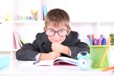 школяр, сидячи на столі в класі