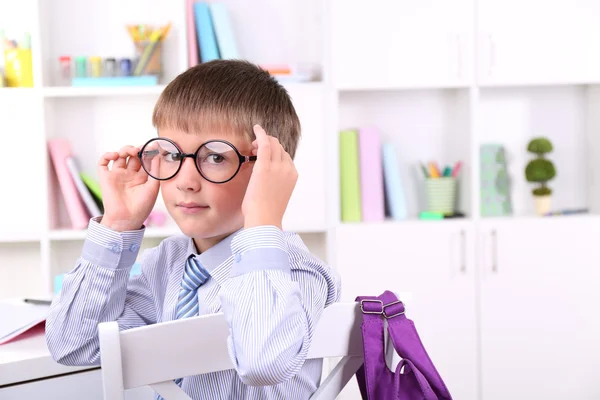 Schooljongen zitten aan tafel in klas — Stockfoto