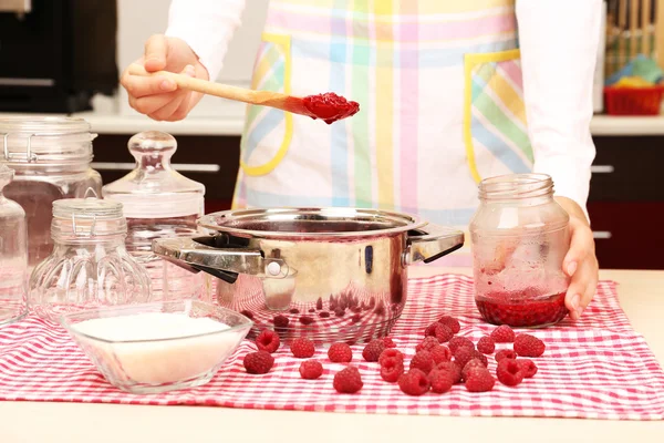 Woman cooking raspberry jam in kitchen — Stock Photo, Image