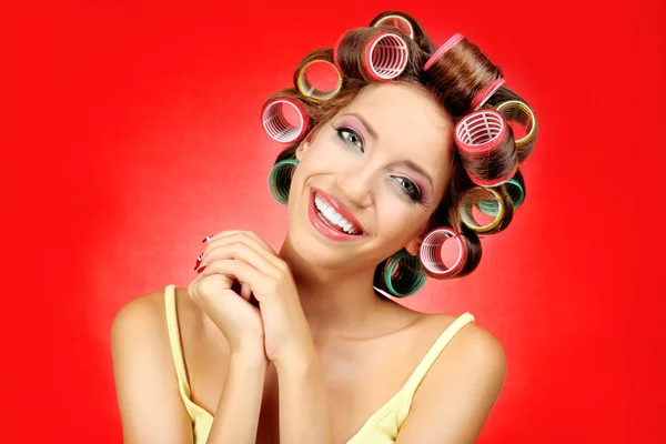 Hermosa chica en rulos de pelo sobre fondo rojo — Foto de Stock