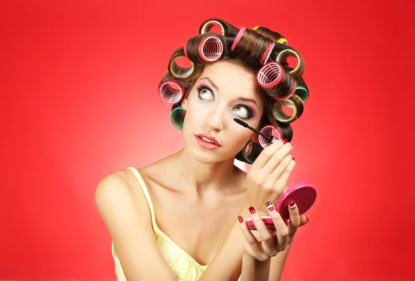 Krásná dívka v natáčky na vlasy na červeném pozadí — Stock fotografie
