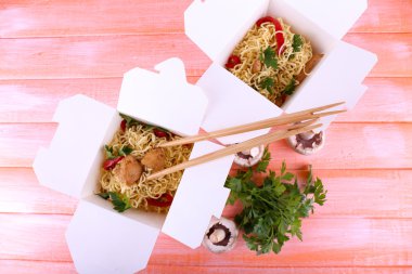 Et ve pembe bir arka plan üzerinde paket servisi olan restoran kutularındaki biber ile Çin eriştesi