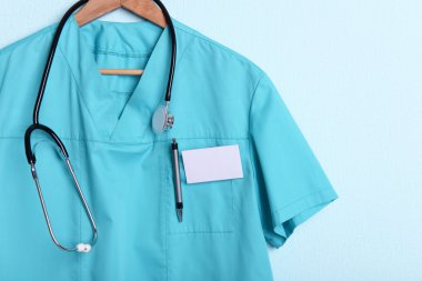 Askı üzerinde mavi arka plan üzerinde stetoskop ile doktor gömlek
